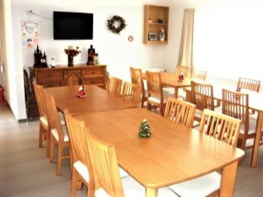 家庭的なリビングにテーブルと椅子が並んでいる様子。木製の家具類が並んでいる