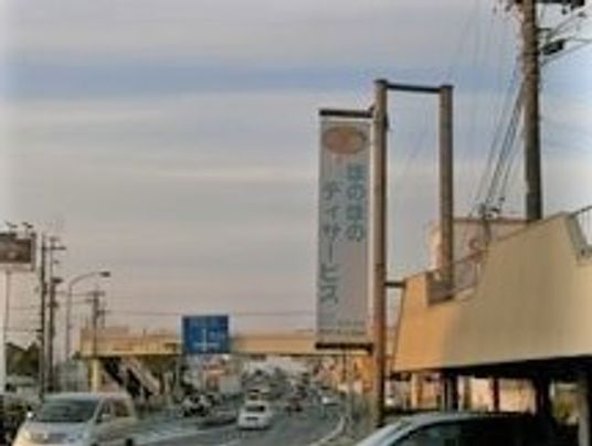 ホームの看板がかかった建物の向こうには車が行き交う道路が見える。