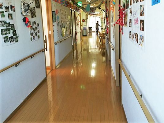 オールバリアフリーの廊下と掲示物が飾ってある壁、手すりが付いている様子