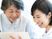なにかを見ながら談笑しているスタッフと高齢者の様子。施設内の会話の場面