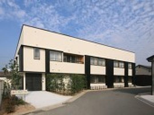 白を基調にしたモダンなデザインのグループホーム。二階建ての建物の外観