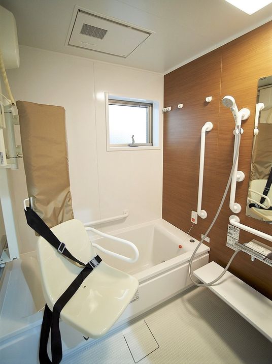 介護仕様の設備と浴槽、手すりが設置されている施設内の浴室の様子