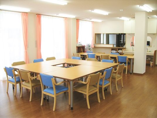 食堂には木製のテーブルが多数並び、奥には対面式のキッチンもある。