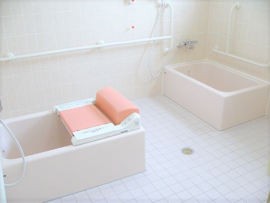 白い個浴が二つセットされた浴室。壁には手すりがあり、多方面から介助ができるよう洗い場が広くなっている。