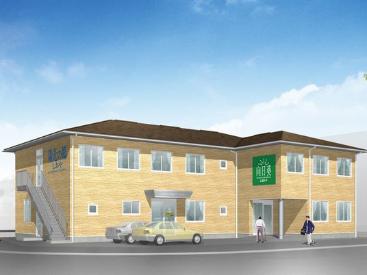 ブラウンを基調とした2階建ての建物。駐車スペースが広く、日がよく当たる立地。