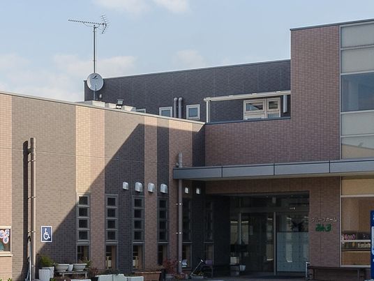 ブラウン系の建物は大きく、玄関の周りにはプランターがたくさん置かれている。日当たりのいい場所に建っている。