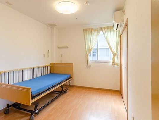 介護ベッドやエアコン、緊急通報装置もあるフローリングの部屋には大きな窓が付いている。