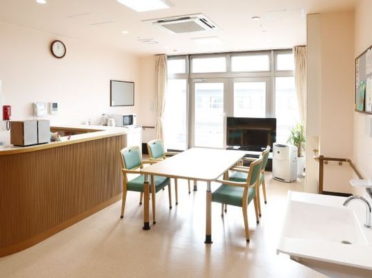 カウンターと洗面台、テレビ、机と四人用の椅子が並べられている部屋の様子