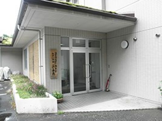 屋根が付いた玄関先にはプランターや傘立てもあり、ハウスの表札も掲げられている。
