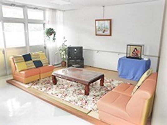 オレンジのソファが対面式に置かれた共有スペースには日本人形や絵画も飾られている。