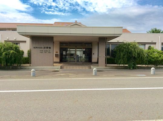 ケアハウスかずきと書かれたベージュの外壁の3階建てケアハウス