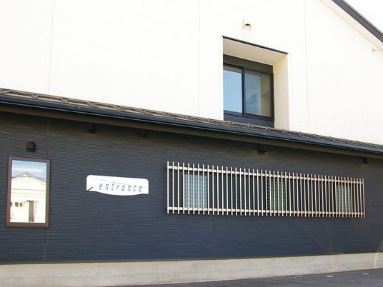白と黒の２階建ての建物。１階部分が黒で、2階部分が白で、1階部分の外壁にはentranceと書かれたプレートが貼られている。