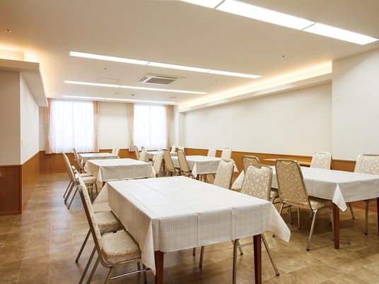四人掛けのテーブルやいすが並べられている施設内の食堂の様子