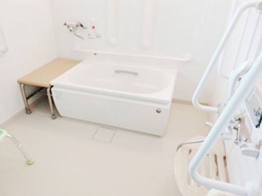 白い浴槽が設置された広い個浴室。シャワーや手すりも設置されている。