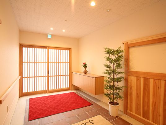 赤い玄関マットが敷かれたエントランスには靴箱や観葉植物も置かれている。
