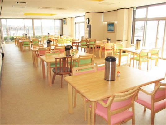 家庭的なサイズのテーブルと椅子が並ぶ食堂の様子。一面採光で明るい空間