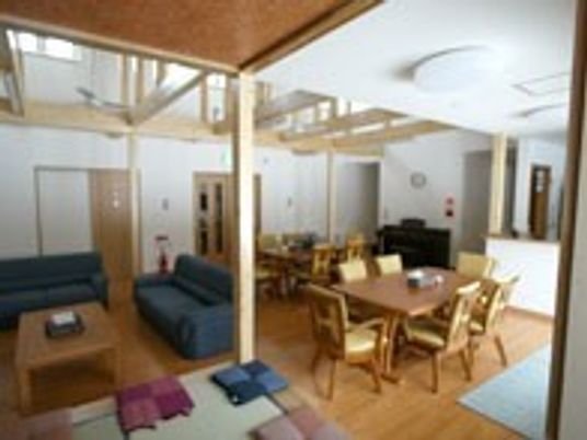 梁のみえる広めの建物。奥にキッチンや個室が写っているのが分かる