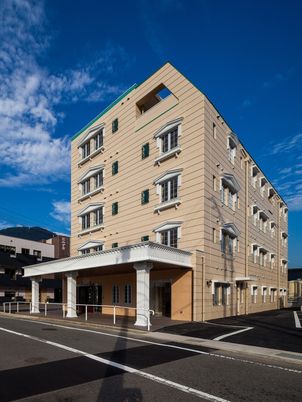 鉄骨造５階建てのウィンザーハウスの外観。エントランス部分に雨の費用の雨除けがついている様子
