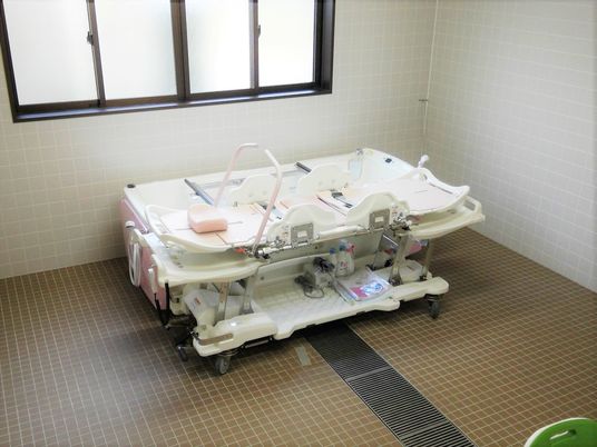 明るい雰囲気のタイル張りの浴室には浴室用の機械浴が完備されている。