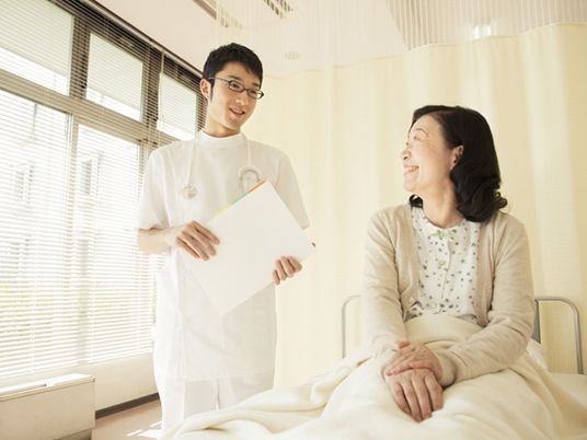 患者と何かについて話しながらほほ笑んでいる看護師の様子。医療機関内の写真
