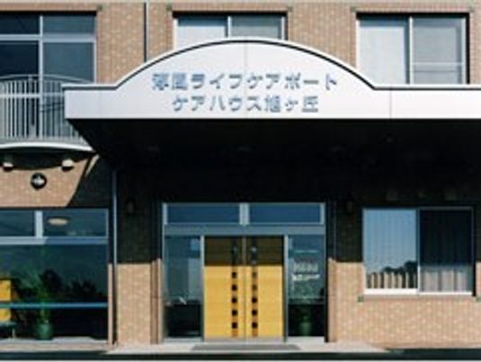 ハウス名が書かれた屋根が付いた玄関には重厚感のあるドアが設置され、レンガ調の外壁はブラウン。窓がたくさんついている。