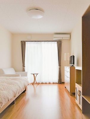 明るい日差しが差し込む施設内の居室の様子。エアコンや介護用ベッドがある様子