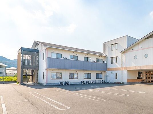 日当たりが良い場所にある高齢者向け施設の外観と駐車場スペースの様子