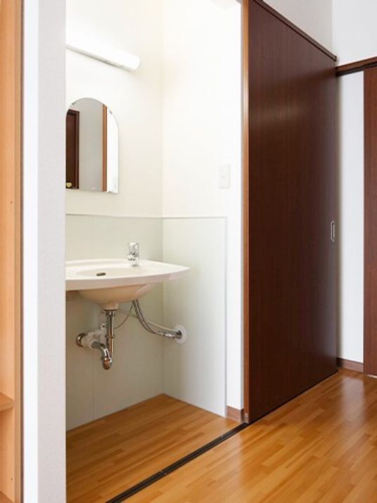 居室内の壁に埋め込むように取り付けてある洗面台。隣にトイレがあるドア