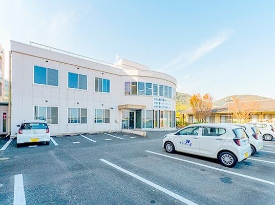 高齢者向け施設の外観と手前にある駐車場スペース。車が止まっている様子