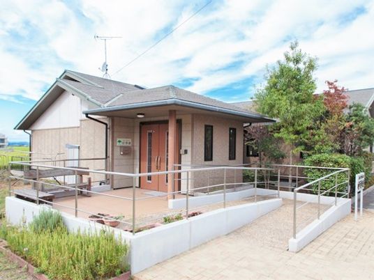 自然に囲まれた平屋建ての建物は手すり付きのスロープが付き、庭もある。