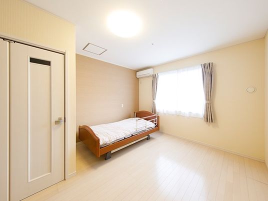 フローリングの一人部屋。布団がセットされたベッドやエアコンがある。
