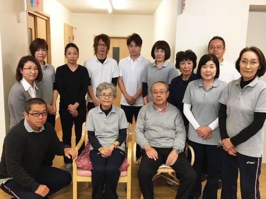 スタッフとほほ笑む高齢者。笑顔でこちらを向いている様子