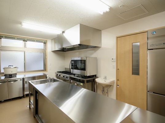 キッチンスペースに炊飯器や電子レンジがある。業務用のキッチンを写した写真