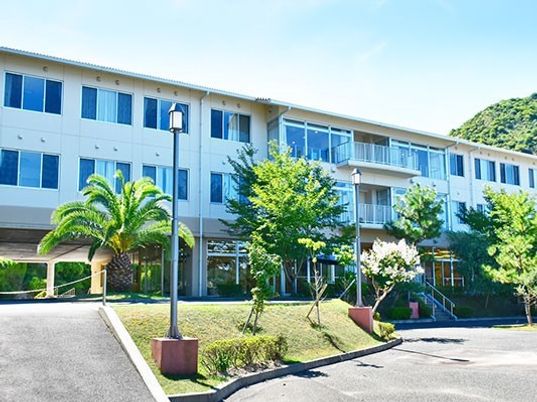 学校のような雰囲気のある鉄骨造の建物。横に長い建物と中庭が写っている写真