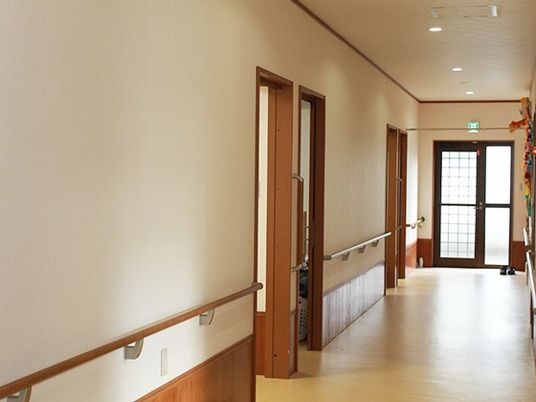 個室のドアと手すりが取り付けてある壁、幅の広い廊下とエントランス