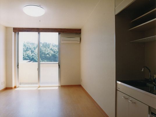 部屋の中からベランダをみた写真。手前にキッチンスペースが見える