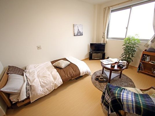 一人用のベッドと小さなテレビがある部屋の様子。ミニテーブルと椅子がある部屋