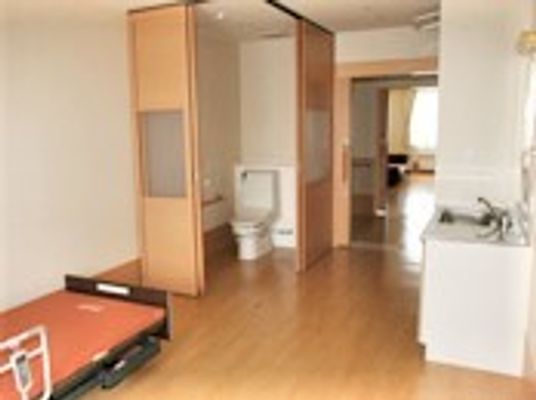 ベッドやトイレ、キッチンなどがそろったフローリングの居室。