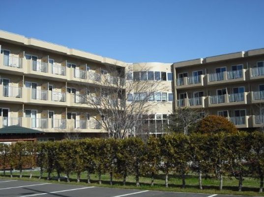 ４階建ての建物はベージュで落ち着いた雰囲気。駐車場も付いている。