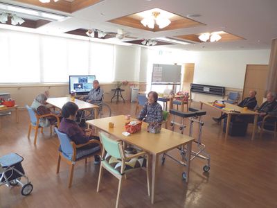 入居者が複数名くつろいでいる食堂には少人数向けのテーブルセットが置かれ、テレビも置かれている。