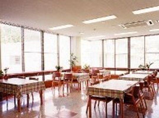 チェックのテーブルクロスがかけられたダイニングテーブルが並んだ明るい食堂。