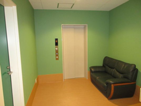 大きなソファが置いてある施設内の一画。モスグリーンの壁紙が印象的な部屋