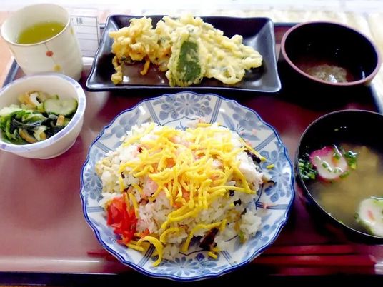 ちらし寿司に味噌汁、野菜の和え物、天ぷらの盛り合わせなどが並んでいる。