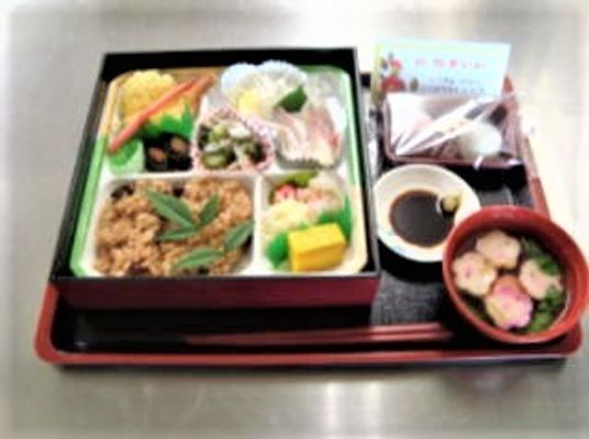 おせち風の食事。昆布巻きや赤飯などめでたい料理がきれいに詰められている。