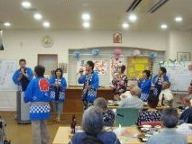夏祭りを楽しむスタッフと入居者の様子。はっぴを着たスタッフが歌を歌っている。 ご入居者様の日々に変化があるよう、季節のイベントもご用意。スタッフが歌や踊りで会を盛り上げます。