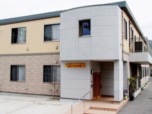 ２階建てのマンションのような建物の外観。エントランスにスロープが付いている様子
