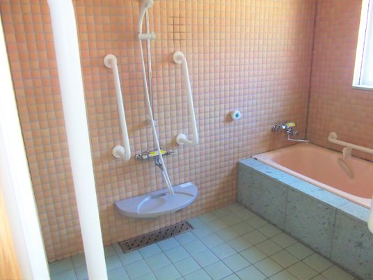 タイルが貼られた浴室にはシャワーや浴槽があり、手すりも多めに設置されている。