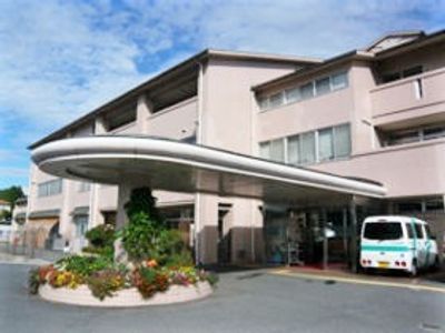 車止めに雨除けのひさしが付いている鉄骨造3階建ての建物。ケアハウス郷原の郷の外観写真
