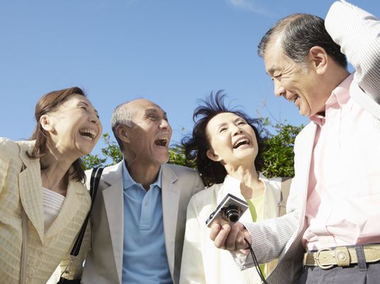 外で楽しそうな表情魅せる2組の高齢者夫婦。青空が広がる気持ち良い日の１枚