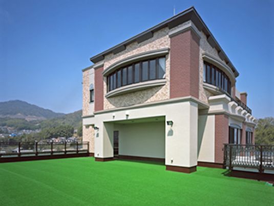 人工芝が敷かれた広い屋上スペースの周りには柵がつき、周辺の街並みを眺めることができる。レンガ調の外壁がおしゃれな雰囲気。